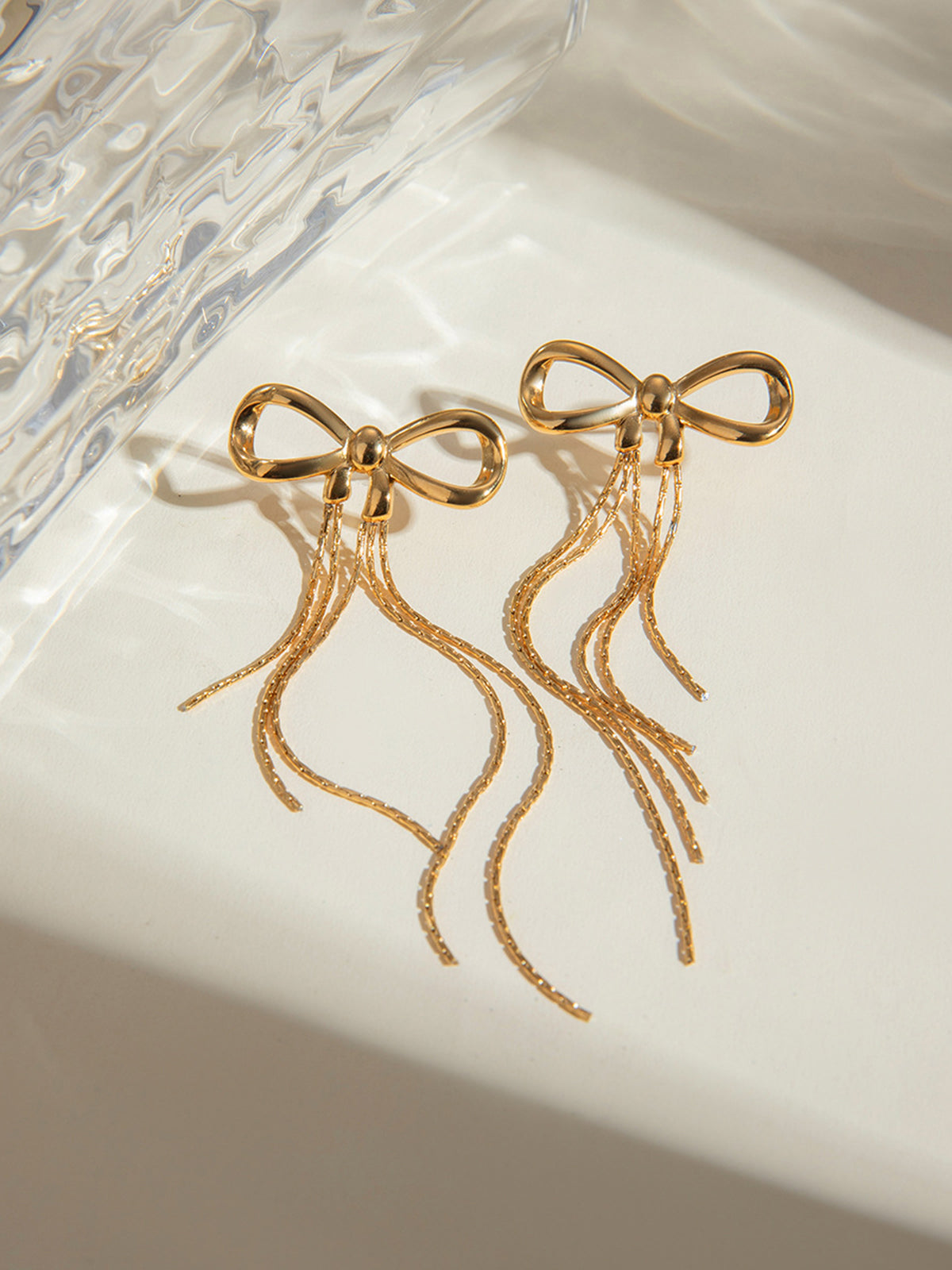 Earring hoops with a shiny gold bow design